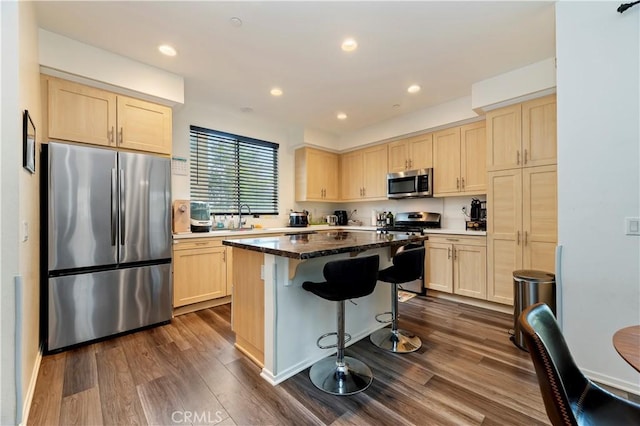677 Savi Dr Unit 101, Corona, CA 92878 - kitchen featuring appliances with stainless steel finishes, light brown cabinets, dark wood-style floors, a breakfast bar, and a center island