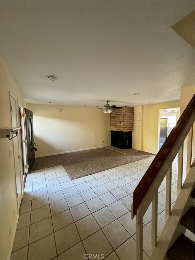 1107 Grieb Dr, Arroyo Grande, CA 93420 - unfurnished living room with light tile patterned floors, light colored carpet, a large fireplace, a ceiling fan, and stairway