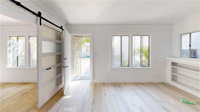 1143 N Sycamore Ave, Los Angeles, CA 90038 - foyer entrance featuring a barn door, wood finished floors, plenty of natural light, and crown molding