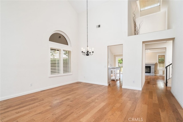 6001 Via De Mansion, La Verne, CA 91750 - unfurnished living room featuring plenty of natural light, a chandelier, light wood-type flooring, high vaulted ceiling, and a stone fireplace