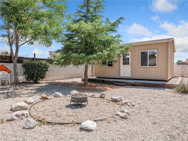 7556 Glider Ave, Hesperia, CA 92345 - rear view of house featuring a fenced backyard, an outdoor fire pit, and an outbuilding
