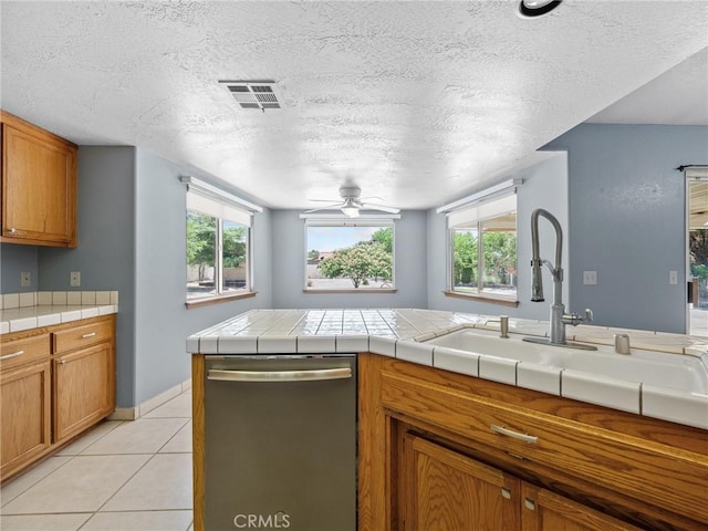 7556 Glider Ave, Hesperia, CA 92345 - kitchen with dishwasher, ceiling fan, brown cabinets, a textured ceiling, and light tile patterned floors