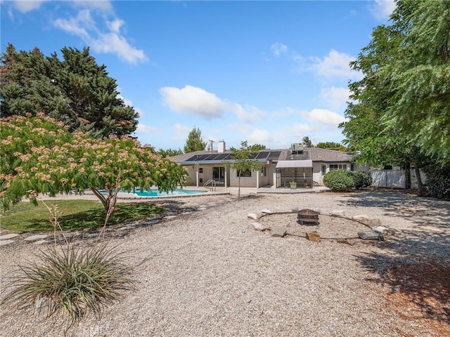 7556 Glider Ave, Hesperia, CA 92345 - back of house with a patio area, an outdoor pool, a fire pit, solar panels, and stucco siding