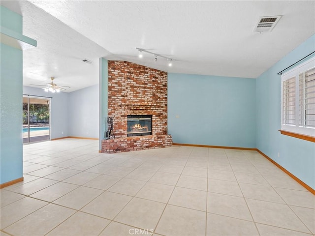 7556 Glider Ave, Hesperia, CA 92345 - unfurnished living room featuring lofted ceiling, rail lighting, ceiling fan, a brick fireplace, and tile patterned floors