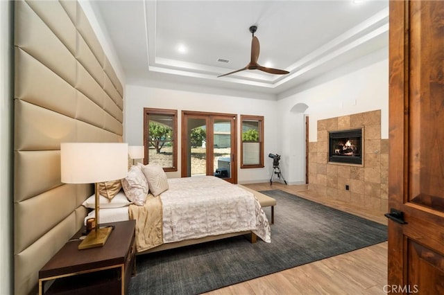 54774 Bautista Rd, Anza, CA 92539 - bedroom with a tray ceiling, wood finished floors, a tile fireplace, arched walkways, and ceiling fan