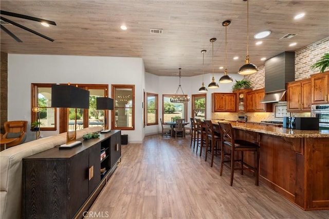 54774 Bautista Rd, Anza, CA 92539 - kitchen featuring brown cabinets, a breakfast bar, light wood-style floors, light stone counters, and hanging light fixtures