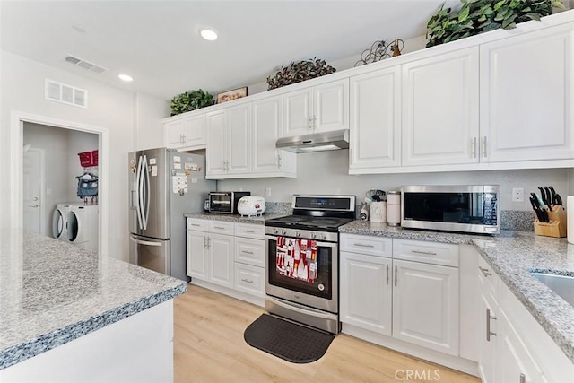 4073 Tamarind Rdg, Lake Elsinore, CA 92530 - kitchen with appliances with stainless steel finishes, washer and dryer, under cabinet range hood, white cabinets, and recessed lighting