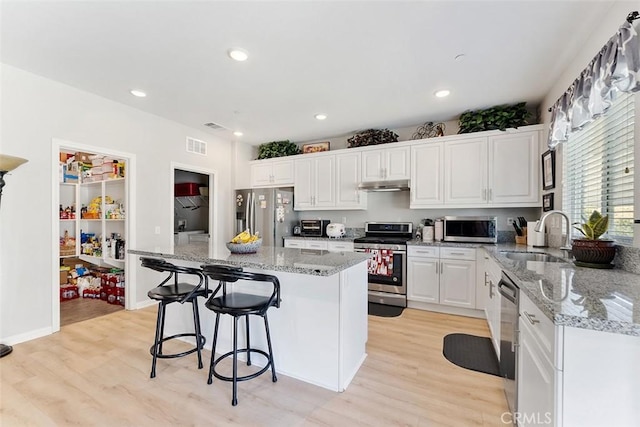 4073 Tamarind Rdg, Lake Elsinore, CA 92530 - kitchen featuring appliances with stainless steel finishes, under cabinet range hood, light wood-style floors, white cabinetry, and recessed lighting