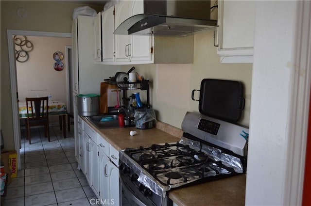 13104 Hoyt St, Pacoima, CA 91331 - kitchen featuring stainless steel range with gas stovetop, exhaust hood, white cabinetry, and light tile patterned flooring