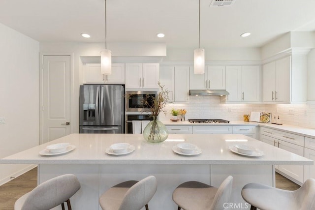 542 Cultivate, Irvine, CA 92618 - kitchen featuring stainless steel appliances, under cabinet range hood, a breakfast bar, white cabinetry, and recessed lighting
