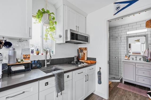 1009 S Cleveland St, Oceanside, CA 92054 - kitchen with stainless steel microwave, dark countertops, dark wood-style flooring, white cabinets, and gas cooktop