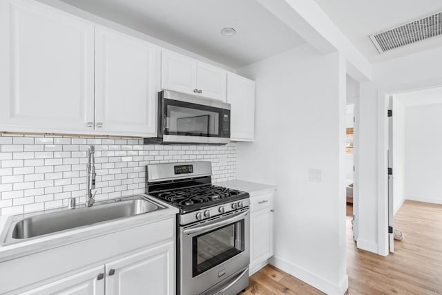 1009 S Cleveland St, Oceanside, CA 92054 - kitchen featuring stainless steel appliances, light wood-style flooring, tasteful backsplash, and white cabinetry