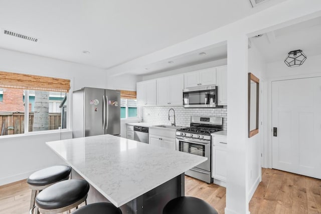 1009 S Cleveland St, Oceanside, CA 92054 - kitchen with stainless steel appliances, white cabinetry, tasteful backsplash, and light wood finished floors