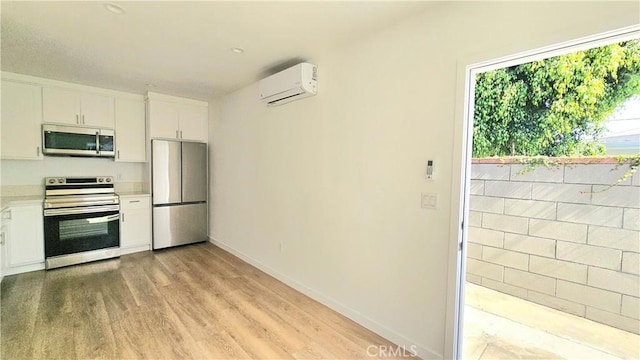 3029 Pacific Ave, Long Beach, CA 90806 - kitchen with stainless steel appliances, a wall mounted AC, light countertops, white cabinetry, and light wood-style floors