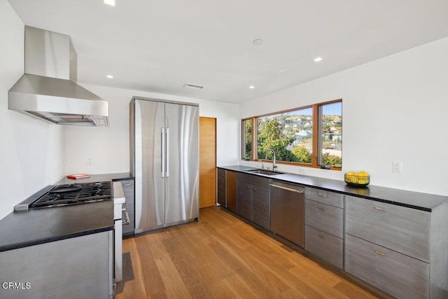 572 Skyline Rd, Ventura, CA 93003 - kitchen with appliances with stainless steel finishes, wall chimney range hood, light wood-style floors, dark countertops, and recessed lighting