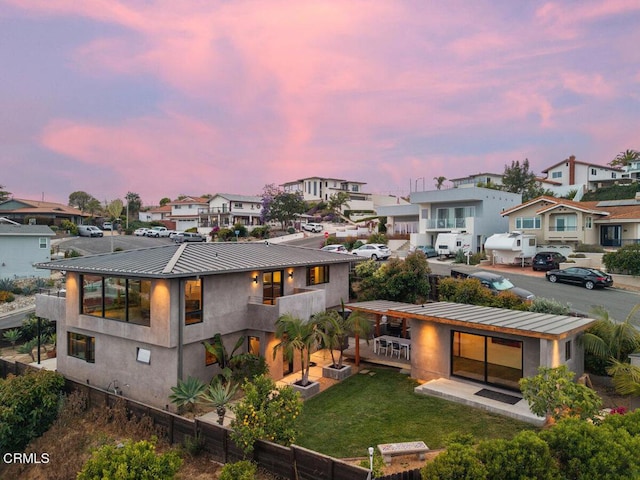 572 Skyline Rd, Ventura, CA 93003 - back of property at dusk with a residential view, stucco siding, a metal roof, a balcony, and a lawn