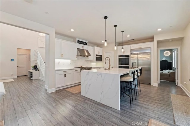 2516 Chad Zeller Ln, Corona, CA 92882 - kitchen with under cabinet range hood, appliances with stainless steel finishes, light wood-style flooring, white cabinets, and recessed lighting