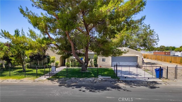 41015 163rd St E, Lancaster, CA 93535 - view of property hidden behind natural elements with driveway, a fenced front yard, a gate, an attached garage, and stucco siding