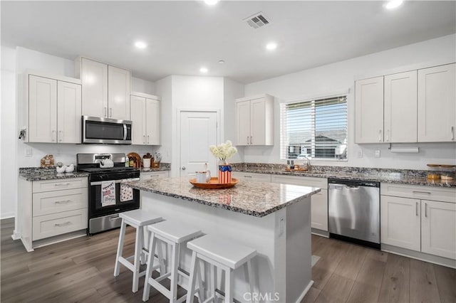12366 Ranchito Way, Victorville, CA 92392 - kitchen with stainless steel appliances, a breakfast bar area, a kitchen island, stone countertops, and dark wood finished floors