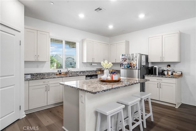 12366 Ranchito Way, Victorville, CA 92392 - kitchen featuring dark wood-style flooring, a breakfast bar area, dark stone counters, a center island, and recessed lighting