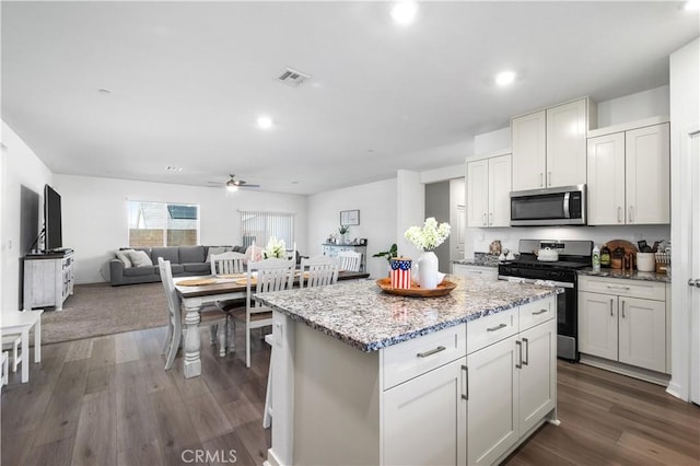 12366 Ranchito Way, Victorville, CA 92392 - kitchen with stainless steel appliances, a center island, ceiling fan, light stone countertops, and dark wood finished floors