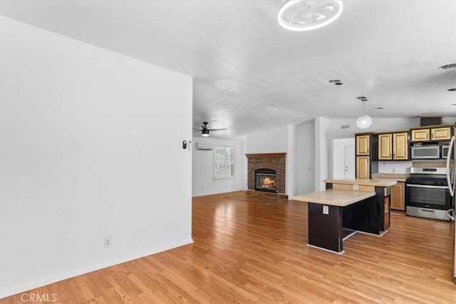 1225 N Alessandro St, Banning, CA 92220 - kitchen with stainless steel appliances, light countertops, a kitchen island, open floor plan, and light wood-style flooring