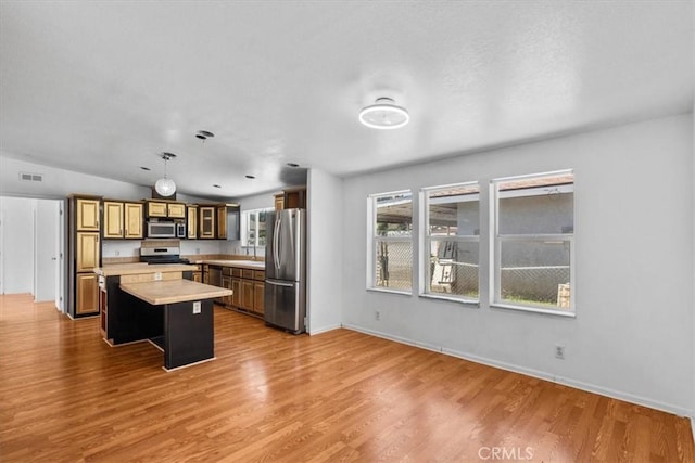 1225 N Alessandro St, Banning, CA 92220 - kitchen with stainless steel appliances, light countertops, a center island, light wood finished floors, and decorative light fixtures
