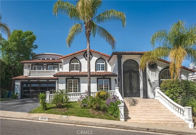 3856 Vista Linda Dr, Encino, CA 91316 - mediterranean / spanish house featuring stucco siding, an attached garage, a balcony, asphalt driveway, and a tiled roof
