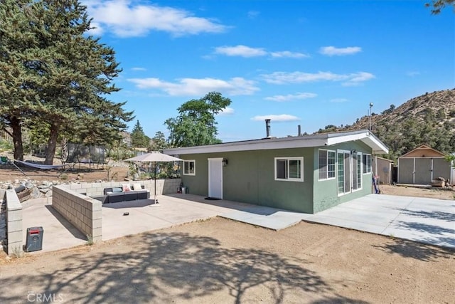 1946 Desert Front Rd, Wrightwood, CA 92397 - rear view of house featuring a patio area, an outdoor living space, a mountain view, stucco siding, and a shed