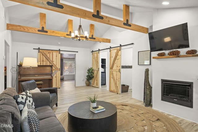 12710 Ojai Rd, Ojai, CA 93023 - living room with a barn door, high vaulted ceiling, beam ceiling, light wood-style floors, and a fireplace