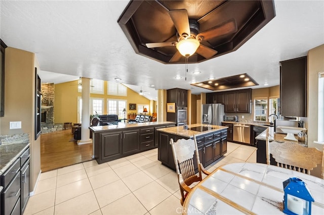 40115 Via Cordova, Temecula, CA 92592 - kitchen with appliances with stainless steel finishes, a raised ceiling, ceiling fan, dark brown cabinetry, and a center island with sink
