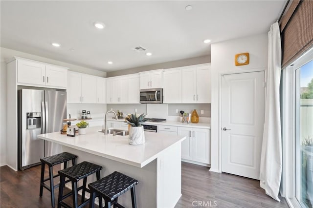 14180 Astra St, Moreno Valley, CA 92555 - kitchen with stainless steel appliances, a breakfast bar, white cabinets, dark wood-style flooring, and light countertops