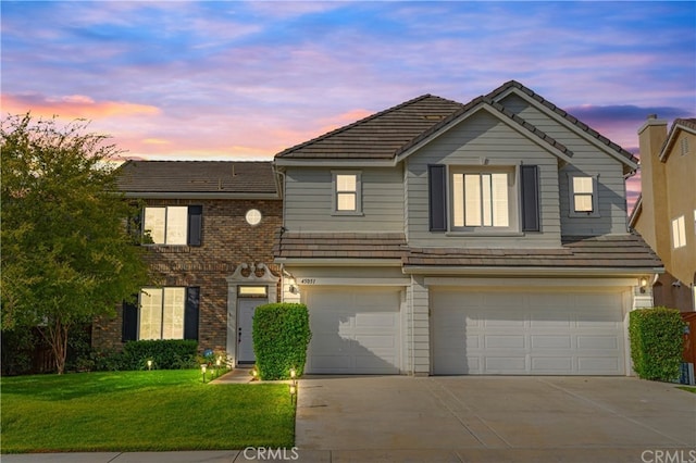 45051 Oakford Ct, Temecula, CA 92592 - view of front facade featuring an attached garage, concrete driveway, a tiled roof, a lawn, and brick siding