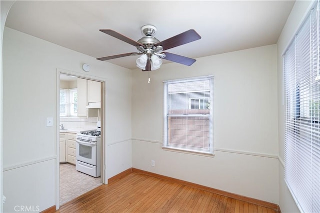 2124 Rutgers Ave, Long Beach, CA 90815 - kitchen featuring white range with gas cooktop, light wood-style floors, ceiling fan, white cabinetry, and light countertops
