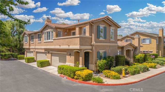 39903 Millbrook Way Unit 7C, Murrieta, CA 92563 - view of front of home featuring an attached garage, a chimney, stucco siding, and a tiled roof