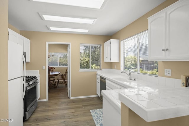 2085 Koala Pl, Oxnard, CA 93036 - kitchen with appliances with stainless steel finishes, wood finished floors, white cabinets, and tile countertops