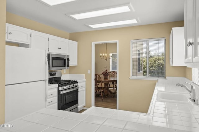 2085 Koala Pl, Oxnard, CA 93036 - kitchen featuring appliances with stainless steel finishes, tile counters, a chandelier, and white cabinets