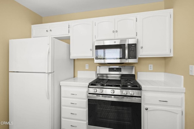 2085 Koala Pl, Oxnard, CA 93036 - kitchen featuring appliances with stainless steel finishes, tile countertops, and white cabinetry