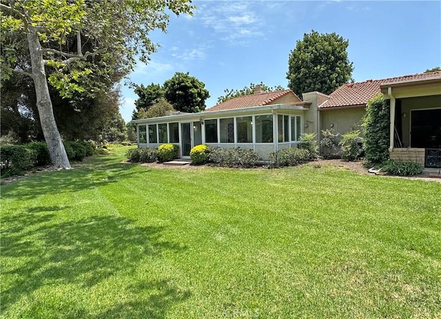 3525 Bahia Blanca W Unit B, Laguna Woods, CA 92637 - back of house featuring a sunroom, a yard, a tile roof, and stucco siding
