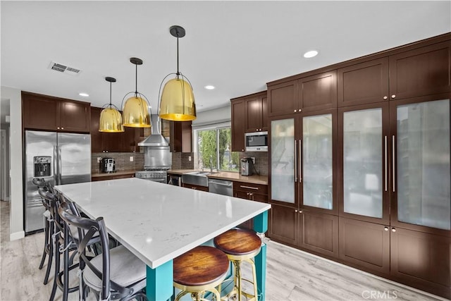 2504 Martingail Dr, Covina, CA 91724 - kitchen featuring stainless steel appliances, light wood-type flooring, wall chimney exhaust hood, a kitchen island, and recessed lighting