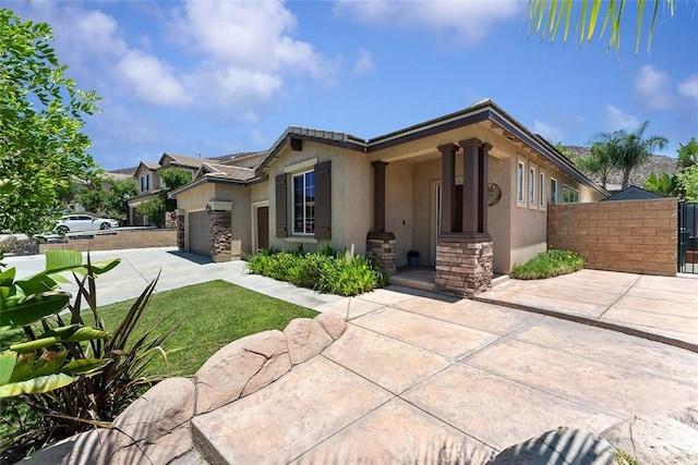 29184 Stone Ridge St, Menifee, CA 92584 - view of front of property with driveway, stucco siding, an attached garage, a gate, and stone siding
