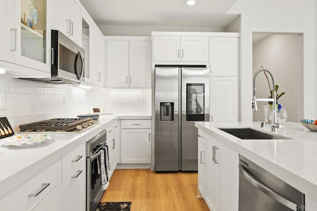 12639 Elizabeth Way, San Diego, CA 92129 - kitchen featuring stainless steel appliances, light countertops, white cabinetry, decorative backsplash, and light wood-style floors