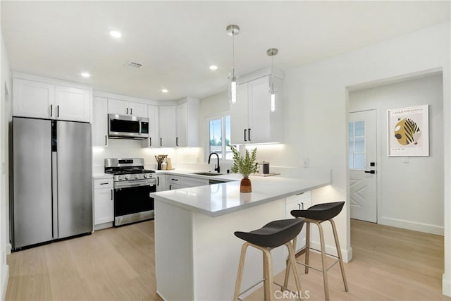 4561 Beverly Ct, Riverside, CA 92506 - kitchen with appliances with stainless steel finishes, a peninsula, light wood-type flooring, white cabinets, and recessed lighting