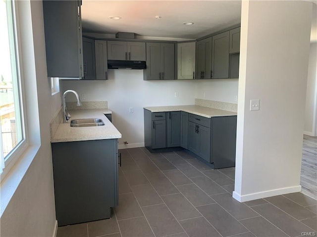 1539 112th St, Los Angeles, CA 90059 - kitchen featuring under cabinet range hood, gray cabinets, dark tile patterned flooring, light countertops, and recessed lighting