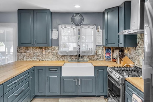 6320 Rancho Rio Rd, Paramount, CA 90723 - kitchen featuring butcher block countertops, wall chimney exhaust hood, stainless steel gas range, and backsplash