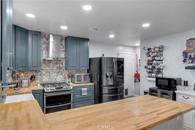 6320 Rancho Rio Rd, Paramount, CA 90723 - kitchen with wooden counters, wall chimney exhaust hood, appliances with stainless steel finishes, decorative backsplash, and recessed lighting