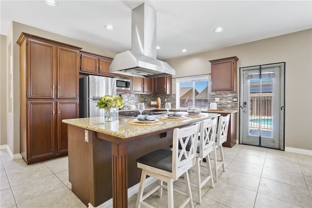 35887 Rhone Ln, Winchester, CA 92596 - kitchen featuring island exhaust hood, stainless steel appliances, backsplash, light stone countertops, and a center island