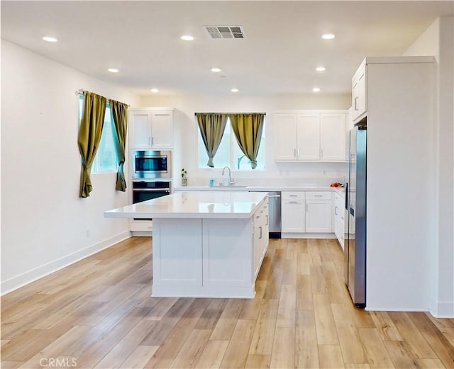 2750 W 182nd St Unit 112, Torrance, CA 90504 - kitchen with appliances with stainless steel finishes, light countertops, white cabinetry, light wood-style floors, and a kitchen island