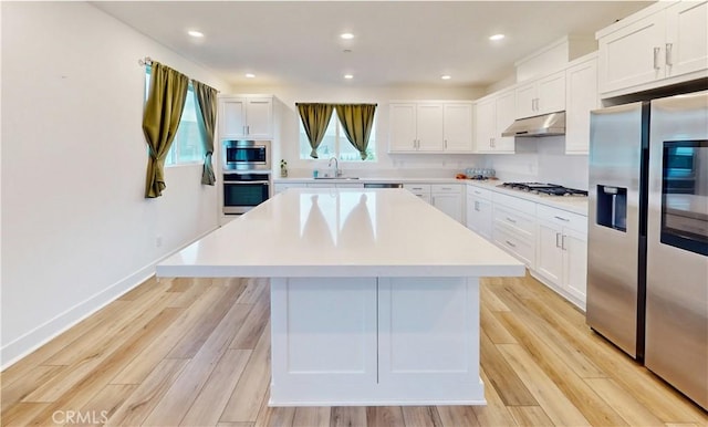 2750 W 182nd St Unit 112, Torrance, CA 90504 - kitchen featuring appliances with stainless steel finishes, under cabinet range hood, a kitchen island, light countertops, and white cabinets