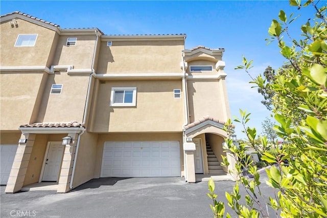 2802 Green River Rd Unit 101, Corona, CA 92882 - townhome / multi-family property with stucco siding, asphalt driveway, a tiled roof, and an attached garage